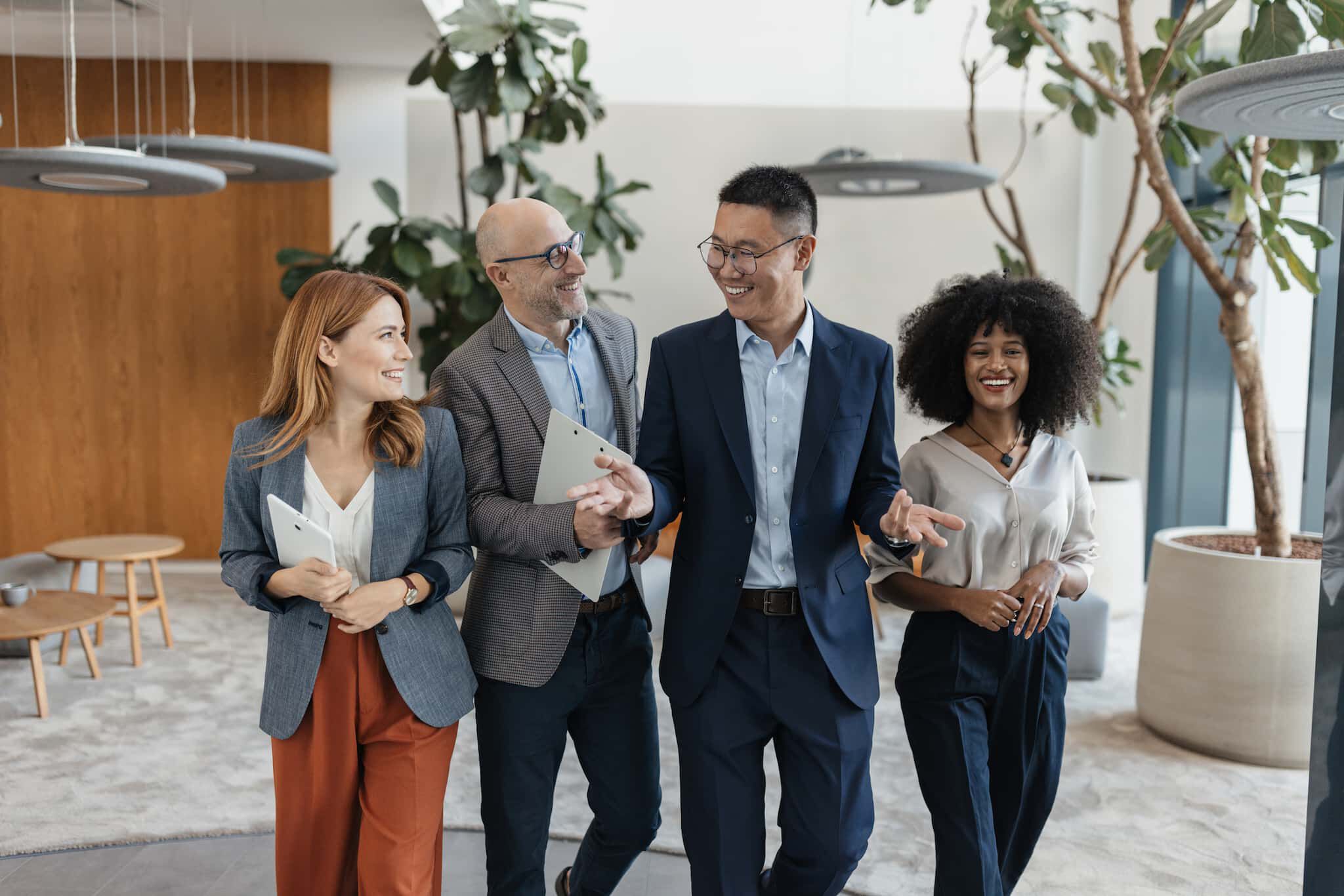 Four professionals standing together in an office, smiling and engaged in a friendly conversation