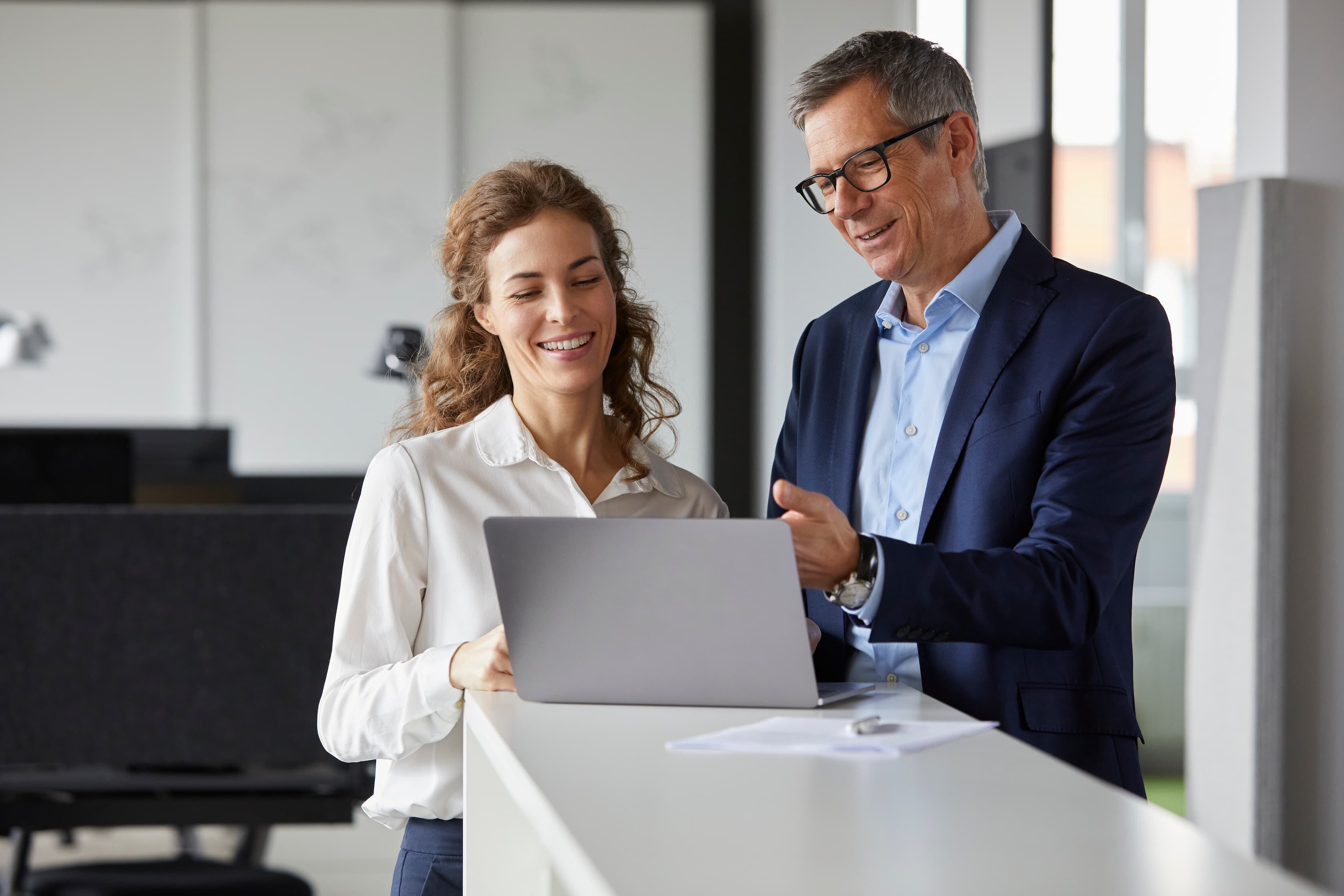 A man and woman are focused on a laptop screen, engaged in discussion